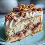 A close-up slice of Decadent Baked Biscoff Cake shows silky Lotus frosting and a generous drizzle of Biscoff spread over the tender, crumbly layers.