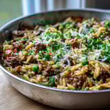 Hearty Comforting Ground Beef Orzo Dinner plated with fresh parsley, served alongside a crisp green salad.