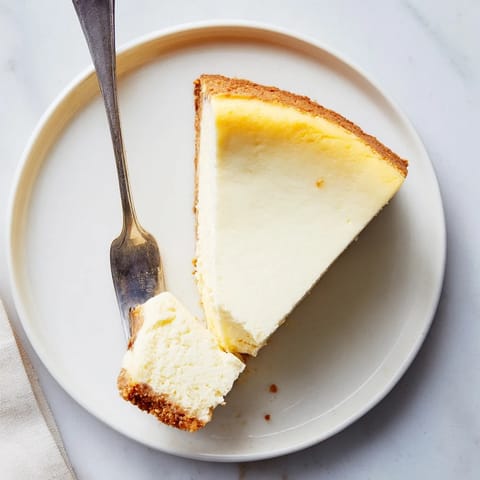 Classic New York Cheesecake slice on a plate, topped with fresh strawberries and whipped cream.