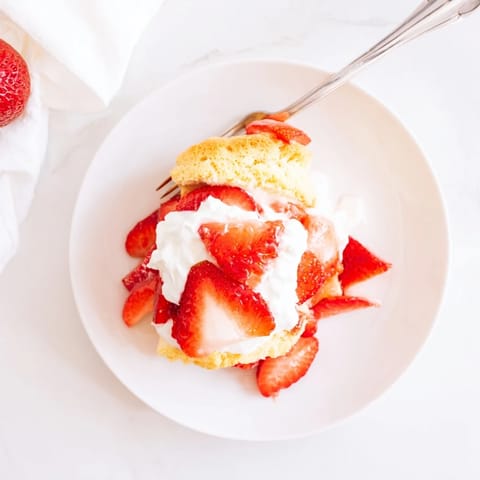 Homemade Strawberry Shortcake biscuits, golden brown and split open, layered with juicy macerated strawberries and fluffy whipped cream.