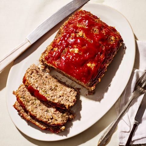 Hearty slices of homemade meatloaf topped with tangy glaze, paired with creamy mashed potatoes and fresh green beans for a comforting meal.