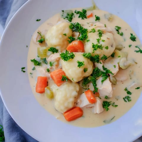 Creamy Chicken and Dumplings in a rustic pot, fluffy dough ready to simmer.