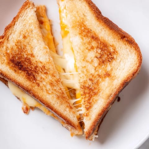 A close-up of a warm Three-Cheese Grilled Cheese sandwich, sliced to show its stretchy, multicolored cheese filling.  