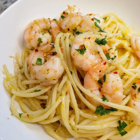 Bright, sautéed shrimp in a lemon garlic butter sauce tossed with al dente spaghetti, garnished with fresh parsley and a lemon wedge for a zesty, flavorful Italian-American main dish.