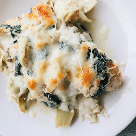 Baked chicken breasts topped with creamy spinach and artichoke mixture, paired with a crisp green salad for a healthy dinner.  