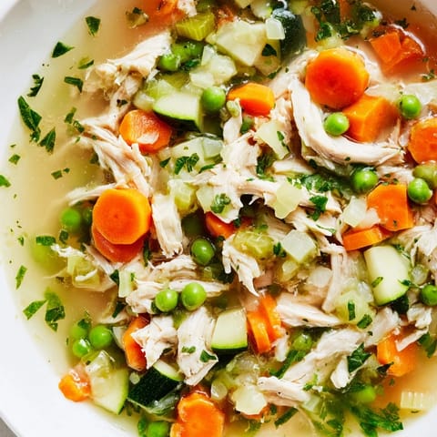Hearty Spring Garden Chicken Soup served in a rustic bowl, garnished with parsley and a lemon wedge for brightness.  