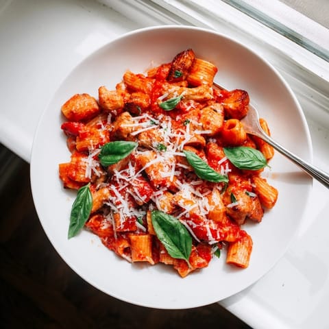 A hearty serving of Tomato Basil Chicken Pasta, paired with a glass of white wine for a perfect weeknight dinner.  
