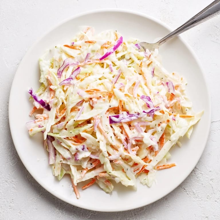 Creamy Coleslaw served on the side with barbecue pulled pork, a refreshing cold salad for sandwiches.