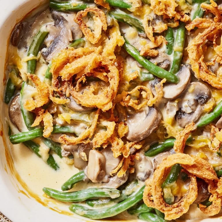 Green bean casserole with tender beans in rich mushroom gravy and crunchy fried onion topping, ready to serve alongside roast turkey.