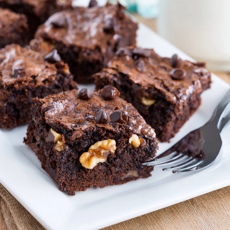 Homemade American brownies on a baking sheet, showcasing glossy dark chocolate and a soft, melt-in-your-mouth texture.