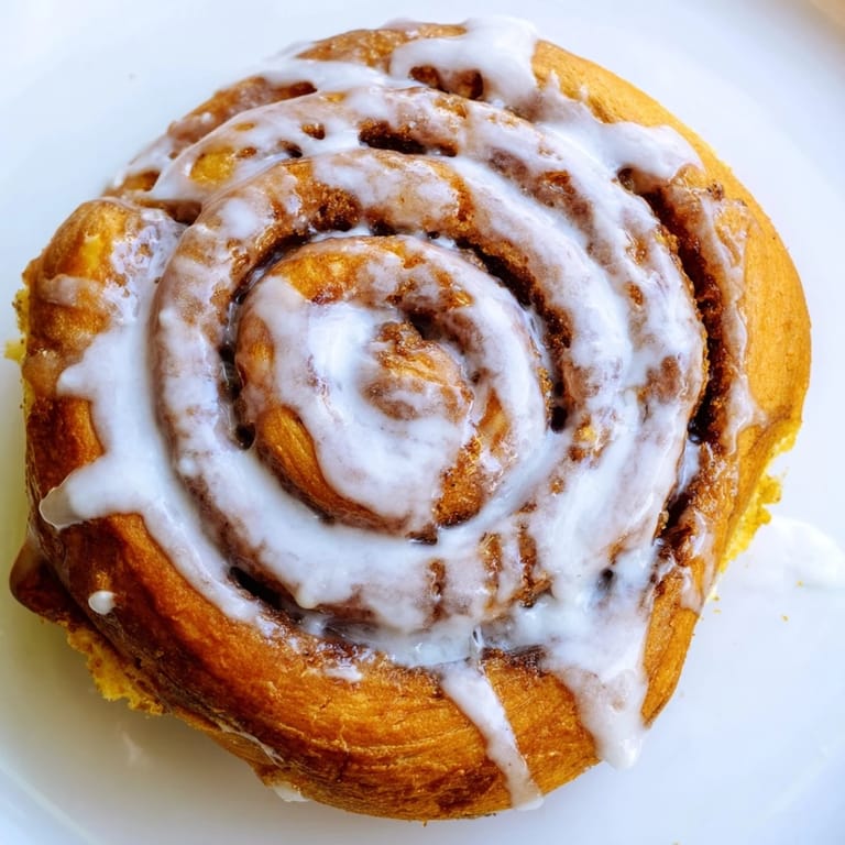Golden Cinnamon Rolls on a rustic table, paired with a steaming cup of coffee for a cozy brunch treat.