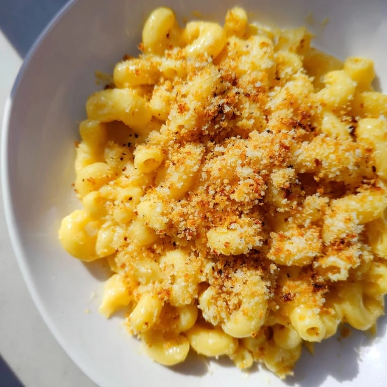 Macaroni and cheese is served warm in bowls, showcasing the creamy, rich cheddar sauce clinging to tender pasta.