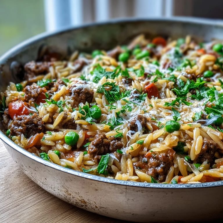 Hearty Comforting Ground Beef Orzo Dinner plated with fresh parsley, served alongside a crisp green salad.