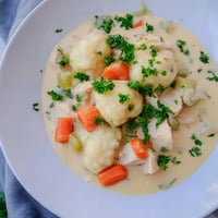 Creamy Chicken and Dumplings in a rustic pot, fluffy dough ready to simmer.