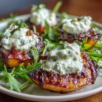 Grilled peaches and burrata cheese on arugula, drizzled with balsamic glaze for a sweet-savory summer salad.