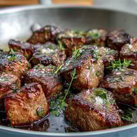 One-Pan Garlic Herb Steak Bites sizzling in a cast iron skillet, golden brown with melted garlic butter and fresh parsley.